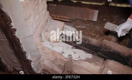 Construction worker restoring an old brick wall using mortar and trowel Stock Photo