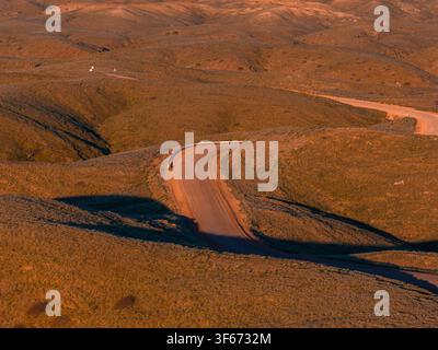 Aerial view of winding dirt road through ochre hills in Namibia at sunset Stock Photo