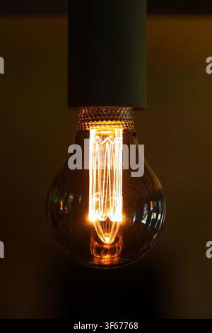 Light bulb switched on close up on dark background vertical Stock Photo
