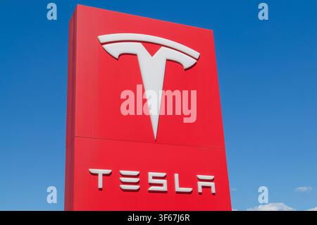 Cadenazzo, Ticino, Switzerland - 3rd July 2026: Tesla white emblem logo and company name on red vertical totem sign outside an official dealership Stock Photo