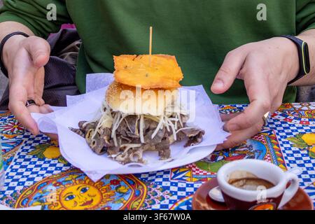 Traditional Palermo street food sandwich Pani câ meusa on colorful street food table. Authentic Sicilian cuisine experience during travel in Palermo, Stock Photo