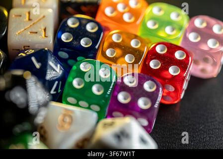 Assortment of translucent red green orange and purple dice displayed closely on dark background Stock Photo