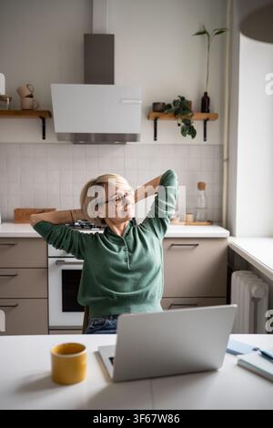Happy businesswoman resting in chair stretching arms and smiling, satisfied after finishing tasks. Stock Photo