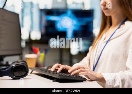 Close up of female engineer writing AI code, developing applications using PC in office. Worker doing internship in startup typing on keyboard, debugging applications using artificial intelligence Stock Photo