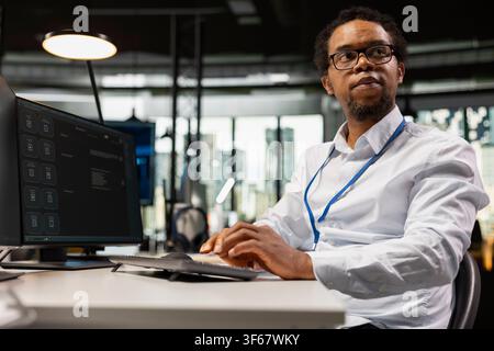 System administrator solving tasks with AI LLM chatbot answering prompts using predictive technology. African american man using computer to interact with large language model program Stock Photo