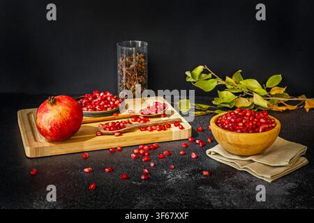 Rustic Still Life of Pomegranate Seeds, Wooden Spoons, and Autumn Leaves on Dark Table Stock Photo