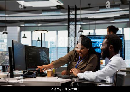 Teamworking programmer and man with paraplegia in office automating tasks with AI scripts. Happy IT expert and colleague in wheelchair using artificial intelligence to speed up feature implementation Stock Photo