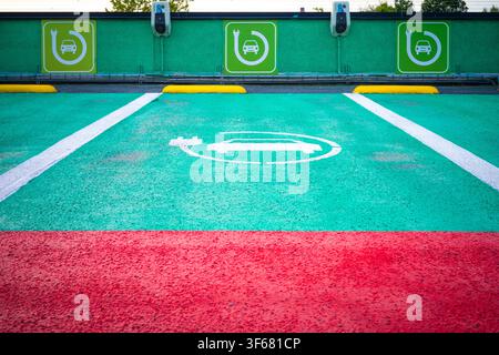 Sint-Niklaas, Belgium, August 1st 2026: Colorful green parking spots for electric car charging. EV or hybrid car charging stations in a parking lot. Stock Photo