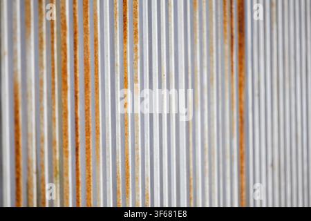 Close-up of a contemporary gate with vertical metal slats in varying shades of gray and rust Stock Photo