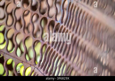 A close-up of a rusty textured, perforated surface with a repetitive pattern Stock Photo