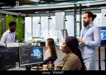 Teamworking engineers writing code, developing machine learning APIs. Team of IT experts in office working together, troubleshooting software errors using artificial intelligence Stock Photo