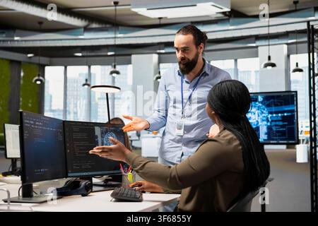 Manager supervising admin adjusting deep learning algorithms parameters to automate tasks. Tech company supervisor overseeing work by staff member using AI insights for code optimization Stock Photo