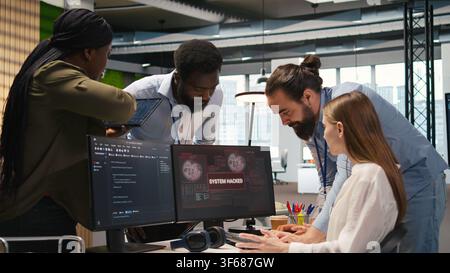Young inexperienced developer in office requests help from team to fix hacking attempt on corporate network. Intern assisted by colleagues to investigate unauthorized access alerts, camera A Stock Photo