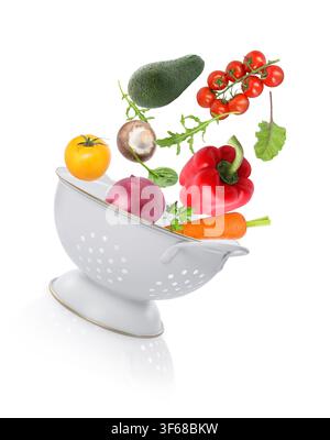 Fresh vegetables and colander in air on white background Stock Photo