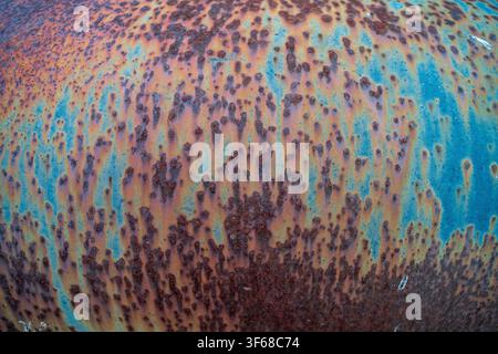 A detailed close-up view of a weathered metal barrel. The surface exhibits a rich patina of rust in various shades of orange and brown. Stock Photo