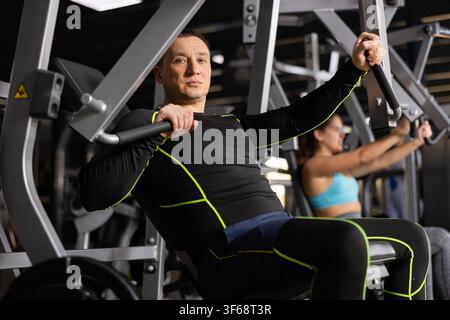 Adult man doing chest press on exercise machine in gym Stock Photo
