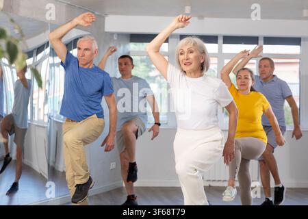 Cheerful elderly woman learning dynamic dances at group choreography lesson Stock Photo