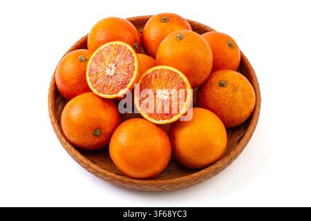 A bamboo basket of fresh raw Tarocco blood oranges with cut halves showing rich red flesh isolated on white background. Stock Photo