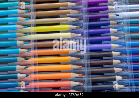 A detailed macro photograph showing an assortment of colored pencils neatly arranged in a multi-tier transparent plastic organizer case. The frame hig Stock Photo