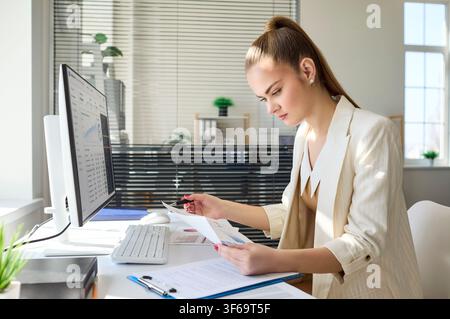 Businesswoman analyzing marketing data at desktop computer in bright modern office Stock Photo