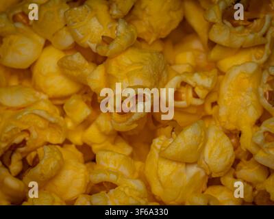 Macro close up of freshly popped yellow buttered popcorn kernels piled together as a tasty snack food background Stock Photo