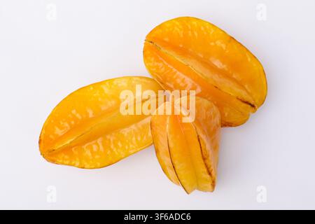 Top-down view of three ripe yellow starfruits on a clean white background. Minimalist studio shot highlighting fresh tropical fruit for healthy eating Stock Photo