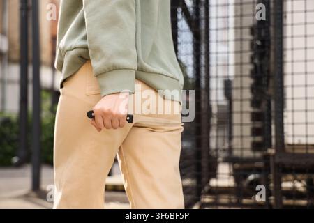 Person holding a knife behind their back, crime and violence concept, danger and threat, urban setting Stock Photo