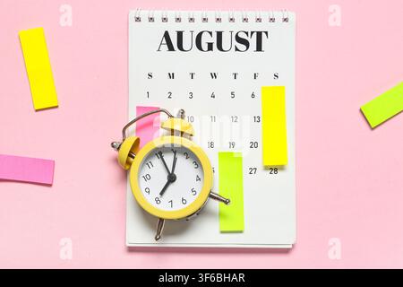 Alarm clock with calendar and sticky notes on pink background. Time management concept Stock Photo