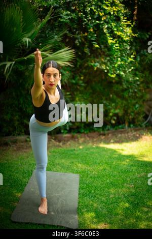 Woman practicing yoga dancer pose in green garden Stock Photo