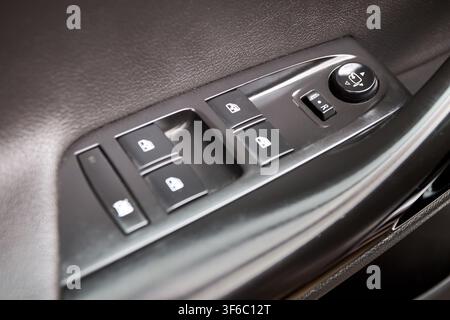 Car door armrest control panel with power window switches, side-mirror adjustment joystick, selective window lock button, black plastic interior desig Stock Photo