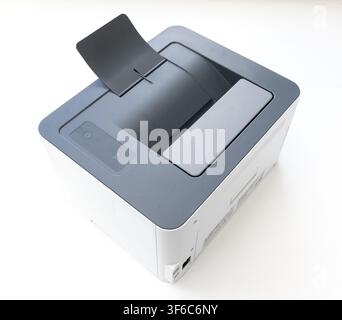 A modern compact laser printer sits on a plain white surface viewed from a high angle Stock Photo