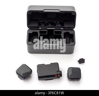 A wireless microphone system with its charging case and components is neatly arranged on a plain white surface Stock Photo