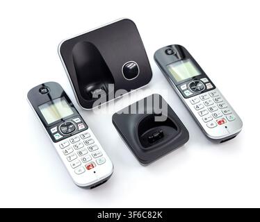 A modern digital cordless telephone set with two handsets and corresponding charging bases is arranged on a clean white surface Stock Photo