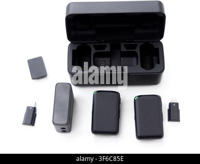 A wireless microphone system with its charging case and various accessories is displayed on a white background Stock Photo