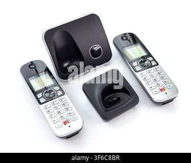 A modern digital cordless telephone set with two handsets and corresponding charging bases is arranged on a clean white surface Stock Photo