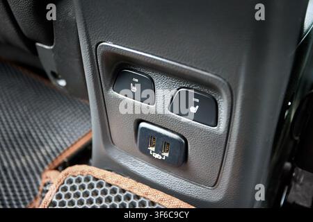 Rear car console features heated seat buttons, dual USB charging ports, textured plastic panel, leather interior details, honeycomb floor EVA mat. Use Stock Photo