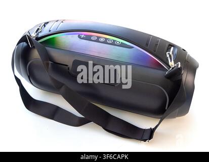 A modern black wireless portable bluetooth speaker with a carrying strap and glowing lights is isolated on a white background Stock Photo