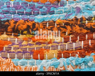 Colorful woven rag rug texture with orange blue and purple fabric threads Stock Photo