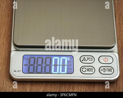 Digital pocket scale with LCD display and control buttons on a wooden surface Stock Photo