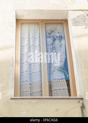 White lace curtain billowing in open window on weathered peeling plaster wall, Olbia, Sardinia, Italy Stock Photo