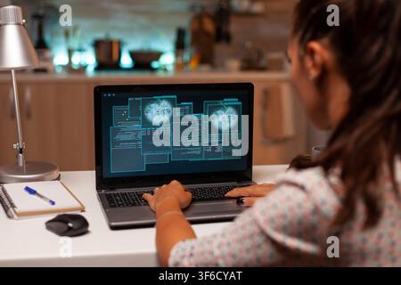 Female hacker tries to crack a security firewall from home while writing dangerous malware on a laptop late at night. Stock Photo