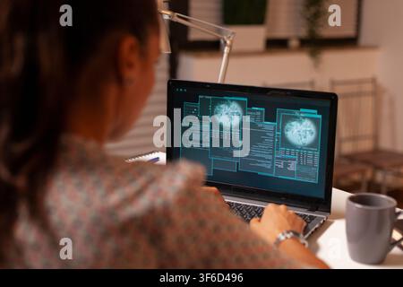 Female hacker uses a home laptop to attack a protected firewall while developing malicious code during the night. Stock Photo