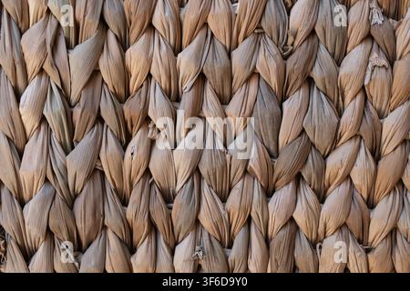 Close up of woven dried palm leaves with a repeating braided pattern, showing natural material, rustic texture and traditional handmade craft. Stock Photo