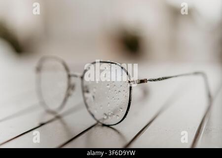 Eyeglasses water spectacles close up of wet thin glasses on a wooden surface reflecting a peaceful mood after rain Stock Photo