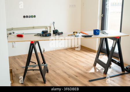 Workbench equipped with various power tools, measuring instruments, and materials during a home renovation.  Stock Photo