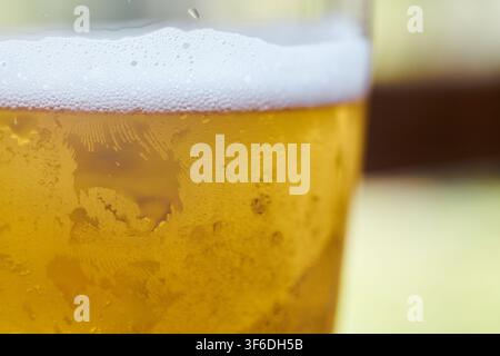Close-up view of a cold glass filled with fresh golden beer showing thick white foam on top and water condensation droplets on the surface of the glas Stock Photo