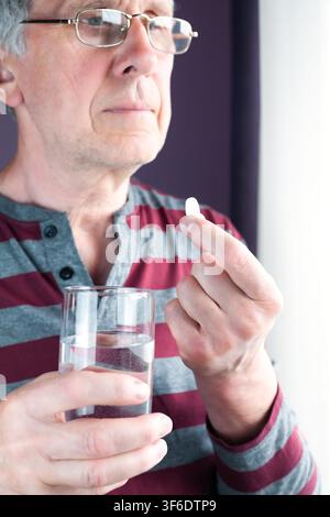 Ill senior man taking medicine. Taking medications with a doctor's prescription. Close-up. Stock Photo