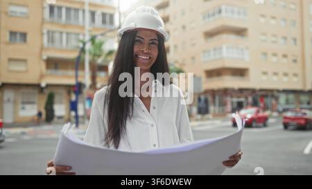 Woman architect holds blueprints with hands while studying plans on urban street building; professional confidence. Stock Photo