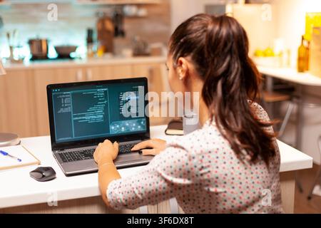 Criminal programmer uses a dangerous virus to target banking information while developing malware for cyberattacks on a laptop at midnight. Stock Photo