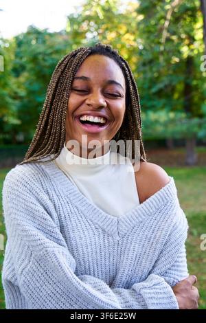 Happy young black woman, standing outdoors in a public park smiling. Stock Photo
